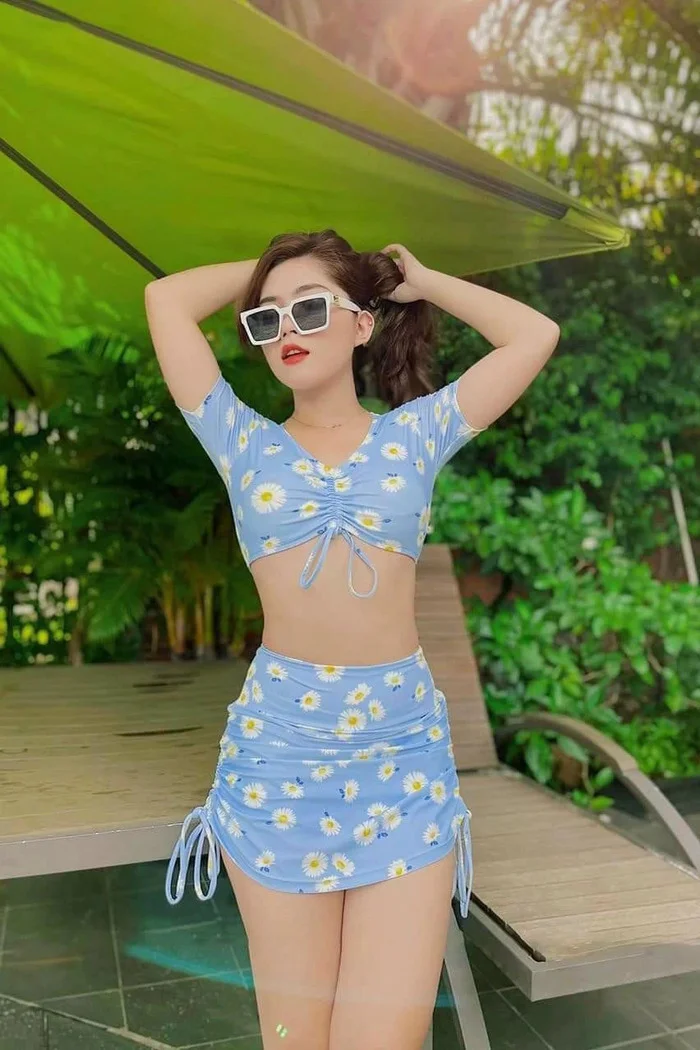 Cô gái mặc bikini xanh họa tiết hoa đứng giữa không gian nhiệt đới