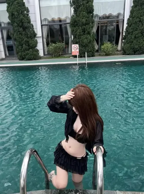 Bikini đen trên người cô gái hiện rõ cạnh thang hồ bơi và tòa nhà trắng.