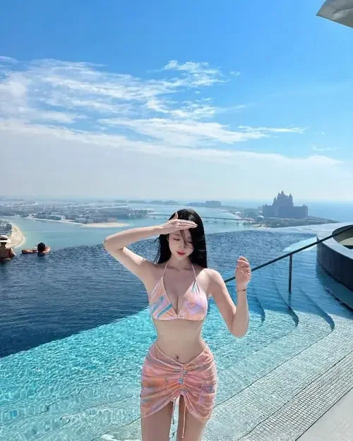 Bikini hồng trên người cô nàng hiện rõ bên hồ bơi vô cực nhìn ra biển.