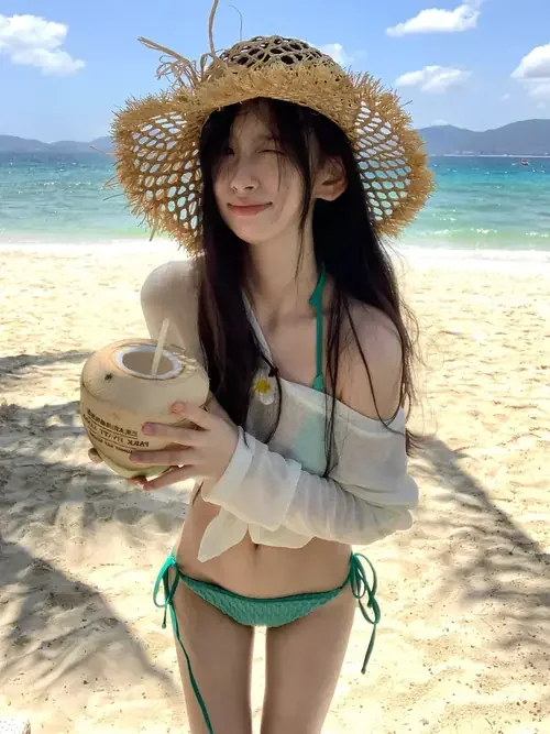 Mũ cói rộng đi cùng bikini xanh nhạt trên người cô gái cầm quả dừa.