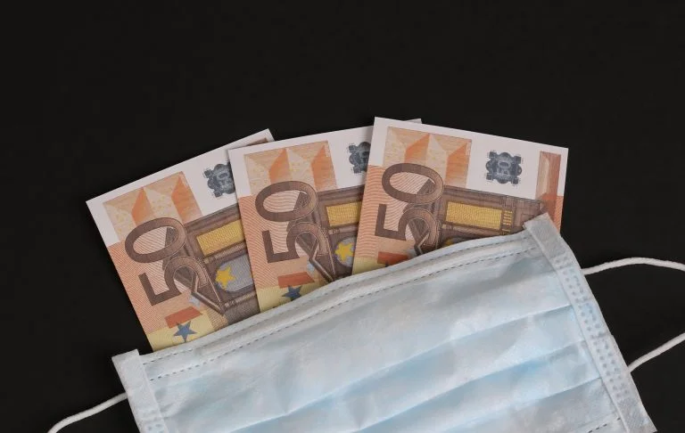 Tiền euro đặt trên khẩu trang y tế nền tối