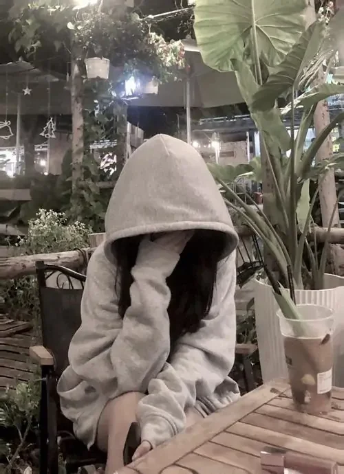Bông hoa hồng đỏ che ngang đôi mắt, cô gái mặc váy trắng đứng trước rèm sáng, mái tóc dài tạo cảm giác mềm và thanh
