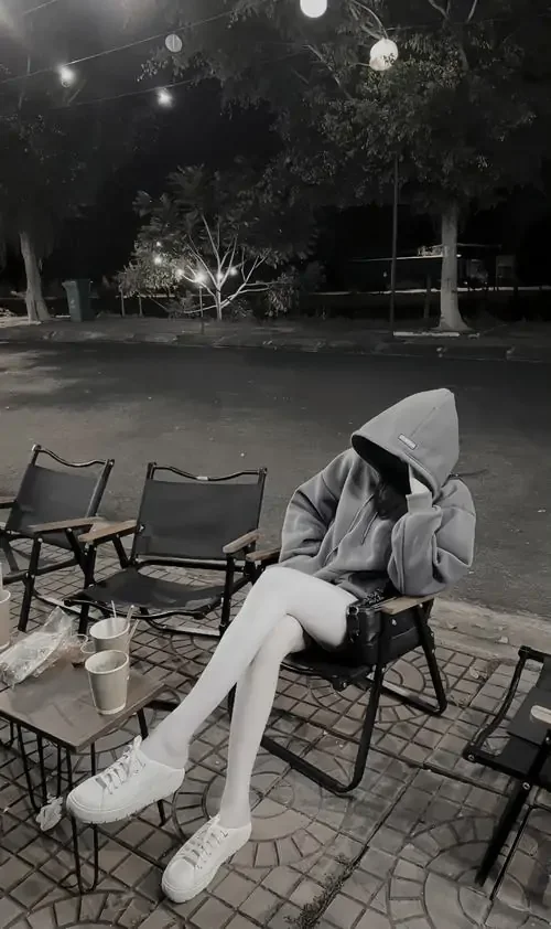 Áo hoodie xám phủ kín dáng ngồi trên ghế, ảnh gái đẹp giấu mặt mang tông đen trắng, chân dài và đôi giày trắng nổi bật