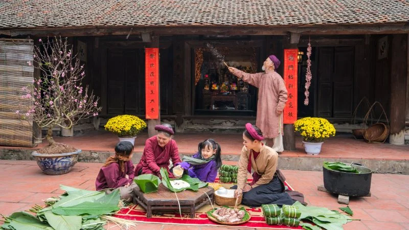 Gia đình gói bánh chưng truyền thống trước sân nhà ngày Tết