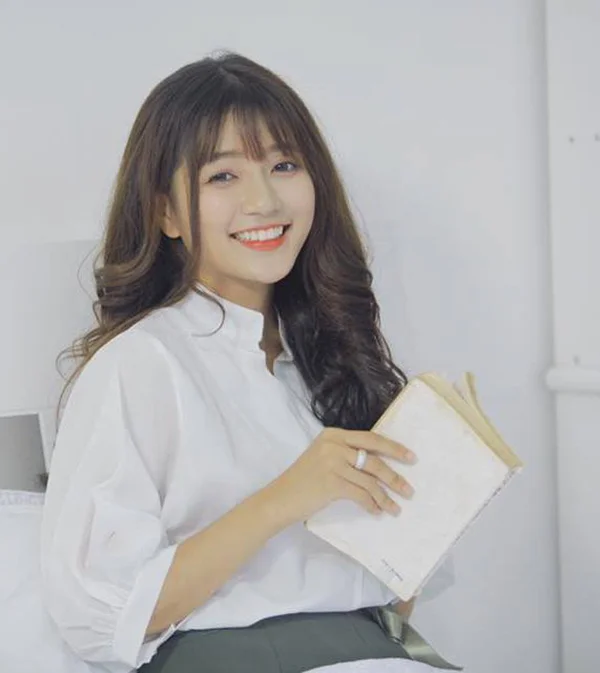 Cô gái xinh cute mặc sơ mi trắng cầm sách